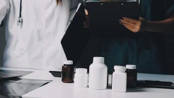 Two doctors are standing around a table with bottles and pills video