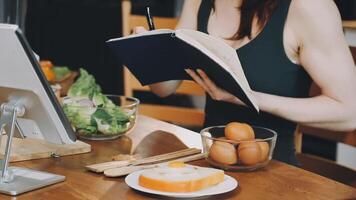 A woman is writing in a notebook while sitting at a table with food video
