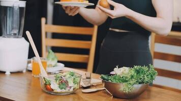 A woman is preparing a salad in front of a blender video