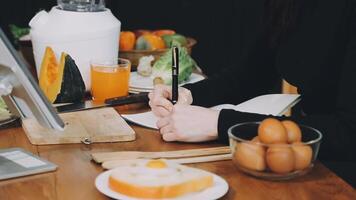 A woman writing on a piece of paper while sitting at a table with food video