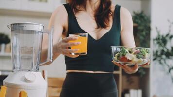 A woman holding a glass of juice and a blender video