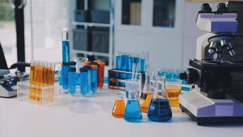 A laboratory table with various chemical flasks and a microscope video