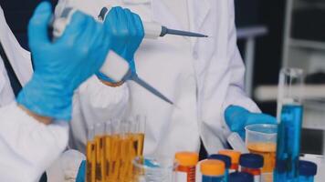 Two people in lab coats and gloves are working on a test tube video