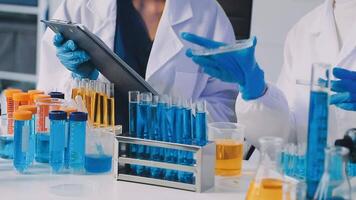 Two people in lab coats are working on a tablet video
