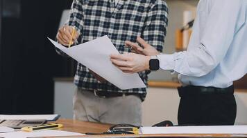 Two men are standing around a table with papers video