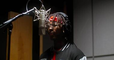 A man with dreadlocks is in a recording studio video
