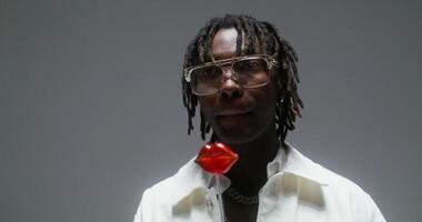 A man with dreadlocks and glasses holding a red object video
