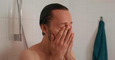 A man is washing his face in the shower video
