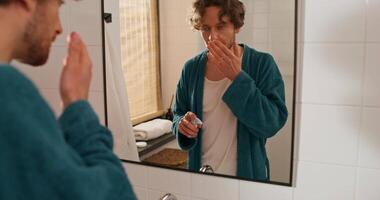 A man in a bathrobe is looking in the mirror video