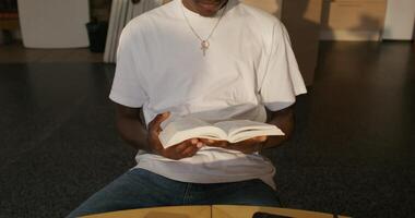 A man sitting at a table with a book and a cell phone video