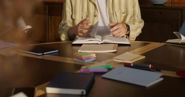 A man sitting at a table with a book and a pen video
