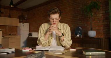 A man is sitting at a table with books and a book video