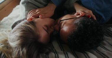 A man and woman laying on a bed together video