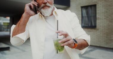A man with a beard and white shirt holding a drink video