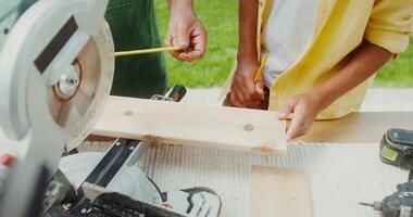 A man and a boy are working on a table saw video