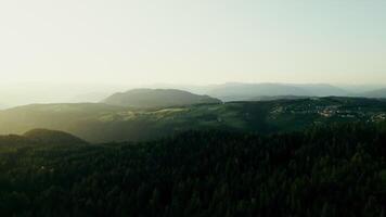 A high-altitude valley with a settlement on top of a mountain at sunset on a summer day, a bird's-eye view from a drone video