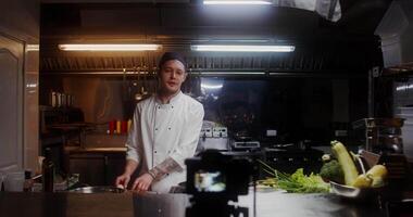 A man in a chef's uniform records the cooking process on by putting bacon in a frying pan video