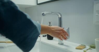 A woman turns on the faucet and washes her hands and face in a stylish bathroom. Close-up of woman's hands under water pressure video