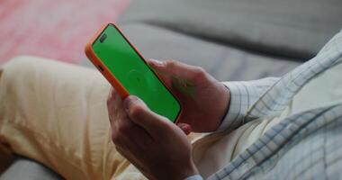 A phone with a green screen in men's hands. The man scrolls the pages with his finger. Close-up of men's hands video