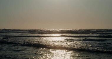Sea waves in the rays of the setting sun. Golden sun rays are reflected in the water video