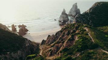The drone flies over the top of the mountain with a view of the sea with a sandy beach and stone reefs near the shore video
