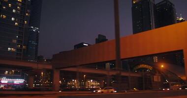 A night metropolis with lots of lights reflected in the windows of skyscrapers. from a moving car video