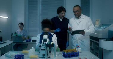 A group of people in a laboratory looking at a tablet video