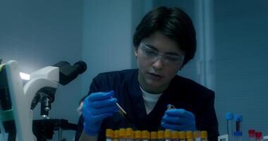 A woman in a lab coat is working on a test tube video