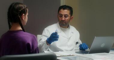 A doctor is talking to a patient while using a laptop video