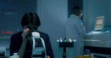A man and woman in a laboratory looking at a microscope video
