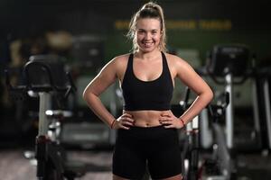A fit woman strikes a confident pose in the gym after an intense workout, showcasing her strength, dedication, and progress. photo