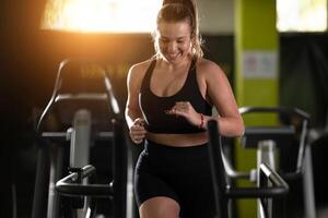 Woman Running on Treadmill in Gym.A fit woman wearing a purple sports outfit is running on a treadmill in a gym. She has a focused yet relaxed expression, with gym equipment and a warm light in the photo