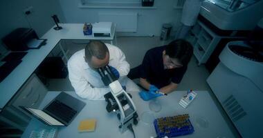 Two men in lab coats looking at microscope video