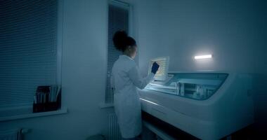 A woman in a lab coat is looking at a computer screen video