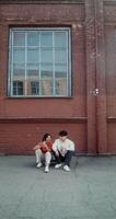 Two people sitting on the ground in front of a building video