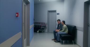 A man and woman sitting on a bench in a hospital hallway video