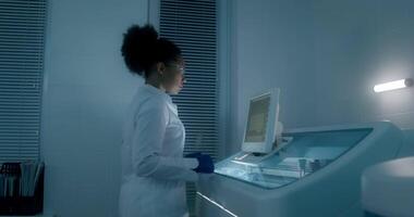 A woman in a lab coat is working on a computer video