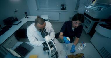 Two people in a laboratory looking at a microscope video