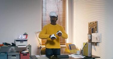 A man in a yellow sweater is standing in front of a desk video