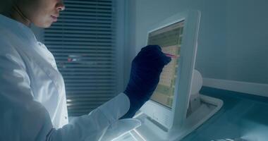 A man in a lab coat is using a computer video