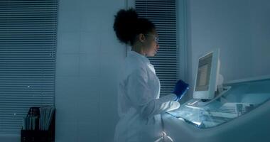 A woman in a lab coat is using a computer video