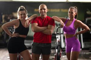 A determined fitness trainer standing confidently in front of his two female clients, guiding them through their workout in the background. photo
