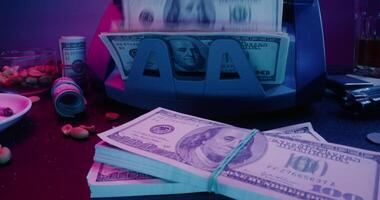 A stack of money sitting on a table next to a money counting machine video