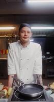 A man in a chef's uniform standing in front of a pan video