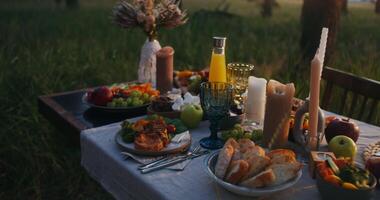 uma mesa conjunto acima com Comida e bebidas dentro a meio do uma campo video