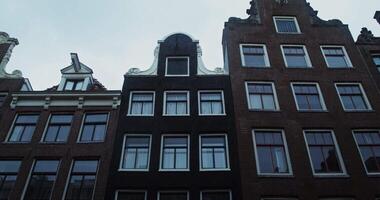 facade van een steen traditioneel huis met wit kaders in de omgeving van de ramen, gedurende regenen, visie van onderstaand. Amsterdam, Nederland 4k , rood komodo video