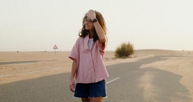 A girl standing in the middle of a desert road video
