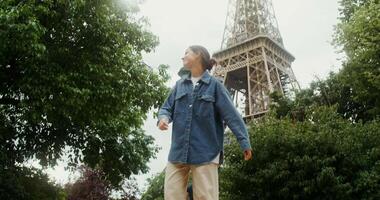 A woman in a denim jacket and jeans standing in front of the eiffel tower video