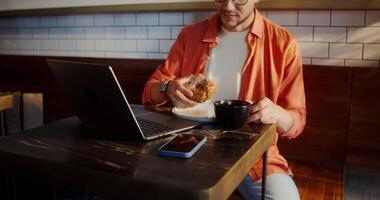 A man is sitting at a table with a laptop and a cup of coffee video
