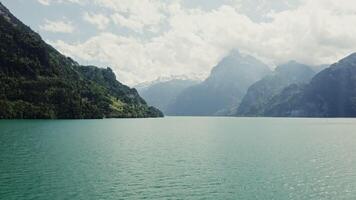 Scenic drone footage of a beautiful lake view at the foot of the Alps in Switzerland. The tops of the mountains are covered with thick white clouds. video